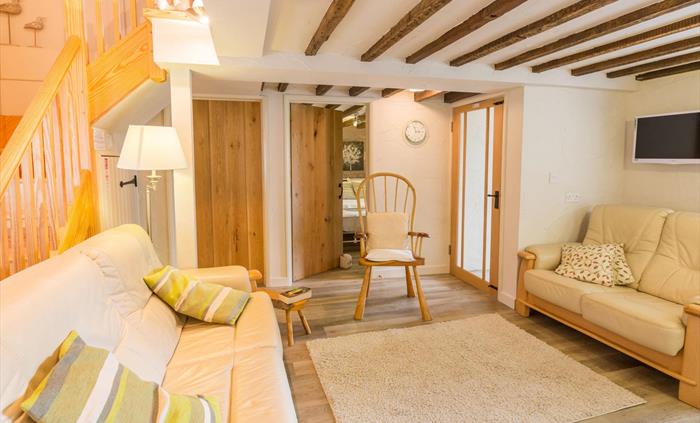 Stangwrach Cottage living room image, beamed ceiling, leather sofas, Easy to clean flooring, removable rugs. Stairs to first floor twin and double roo